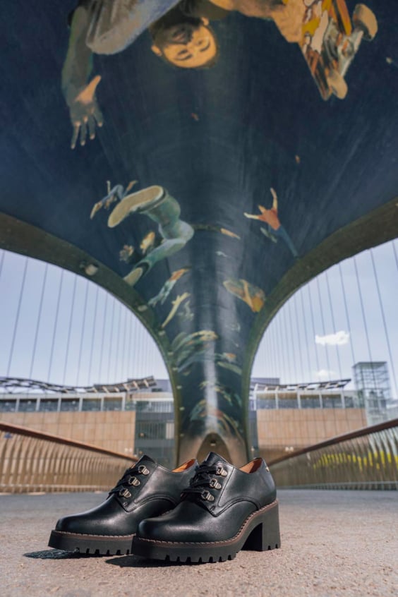 Image of a pair of Pikolinos women's shoes and a covered bridge with illustrations in the background.