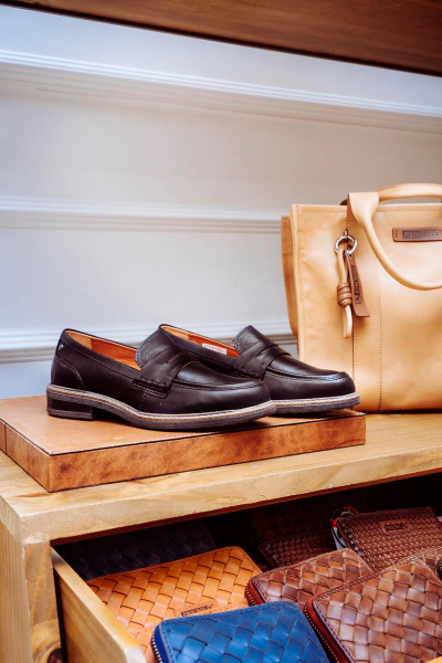 Imagen de unos zapatos Pikolinos sobre un stand donde también se ve un bolso y distintos monederos.