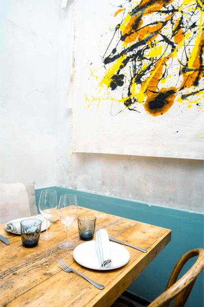 Photograph of the interior of Open restaurant, with one of its tables and a painting in the background.