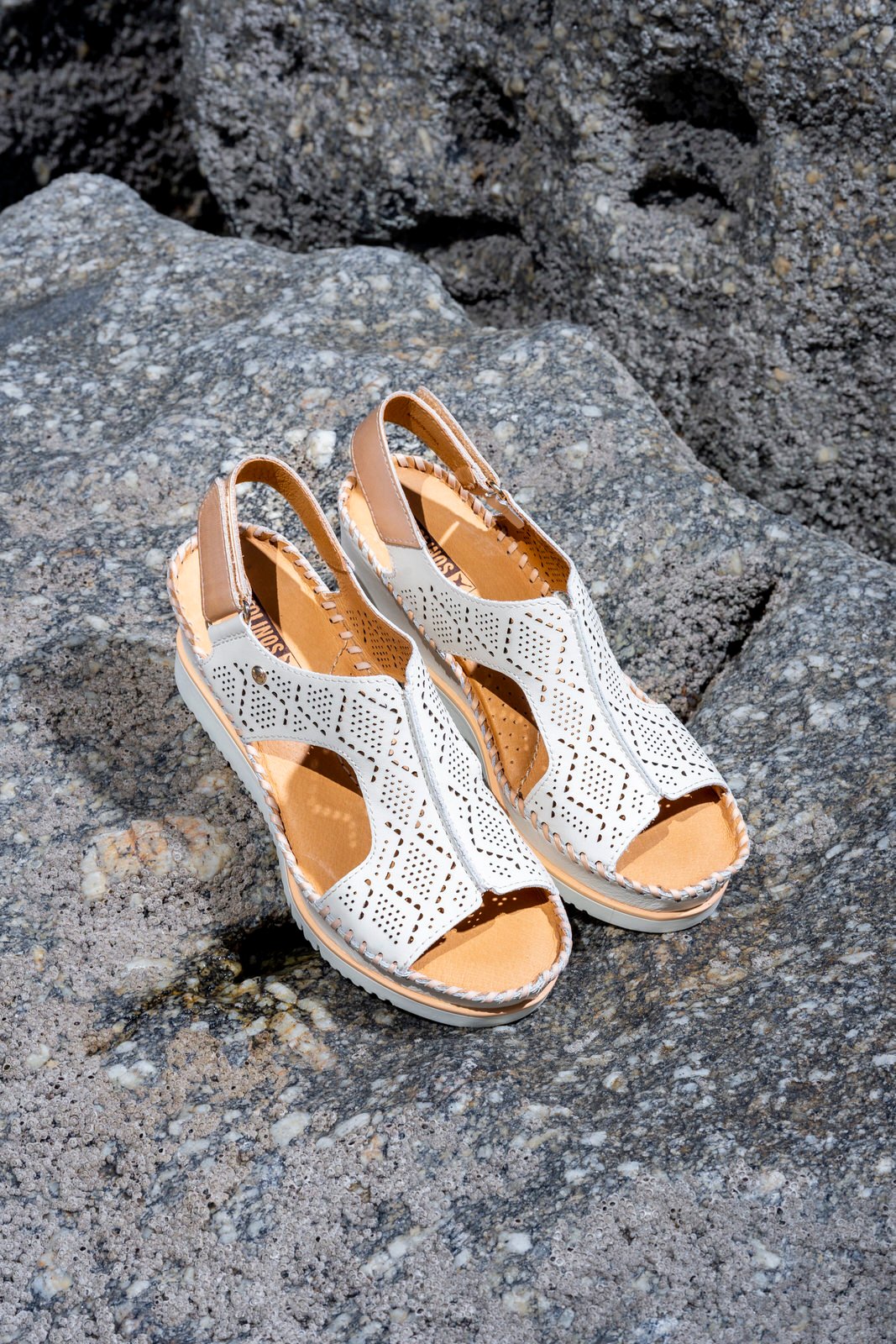 Image of a pair of women's Pikolinos sandals on a rock on the beach