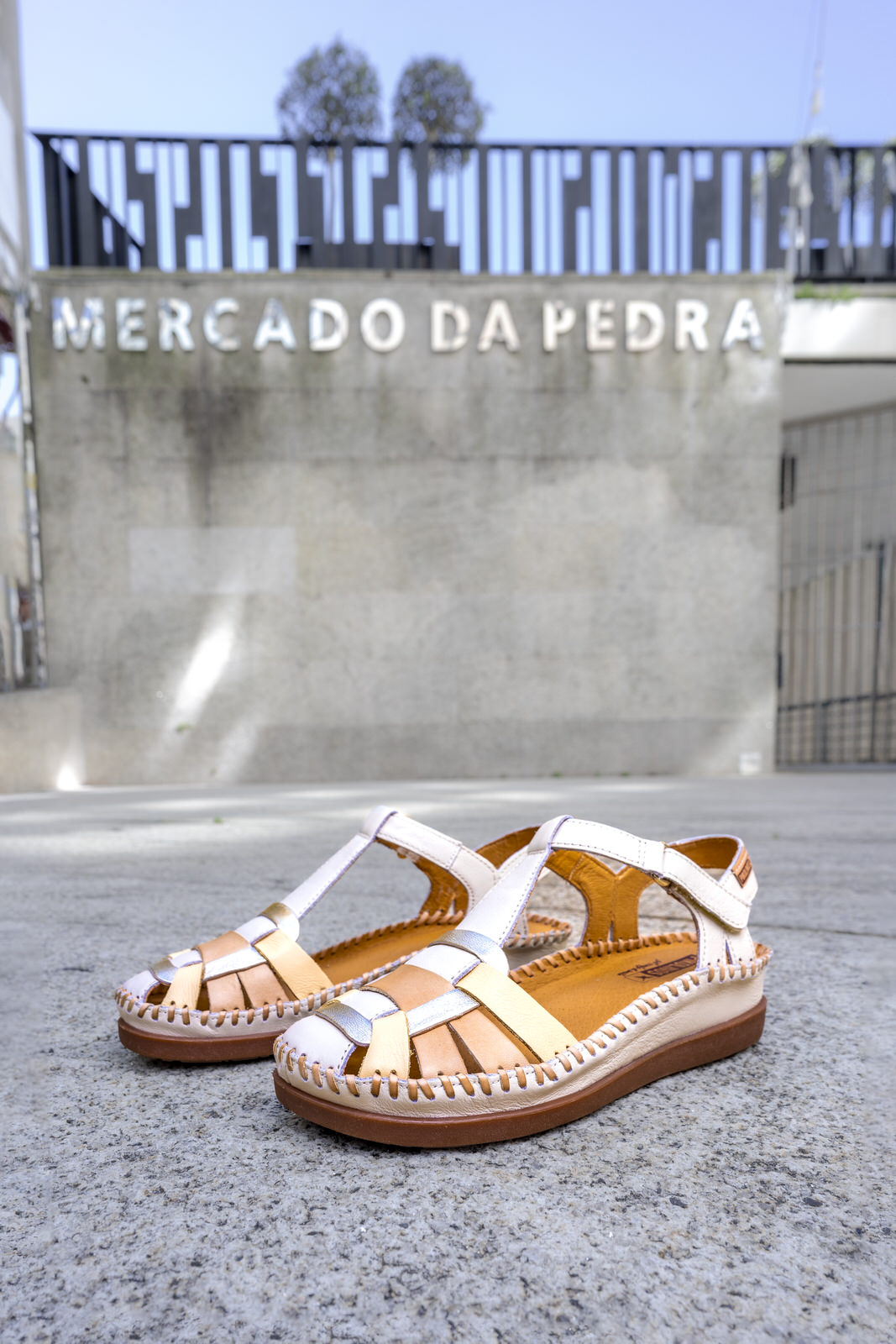 Image of a pair of women's Pikolinos sandals on the ground and, in the background, you can see the Mercado de la Piedra.
