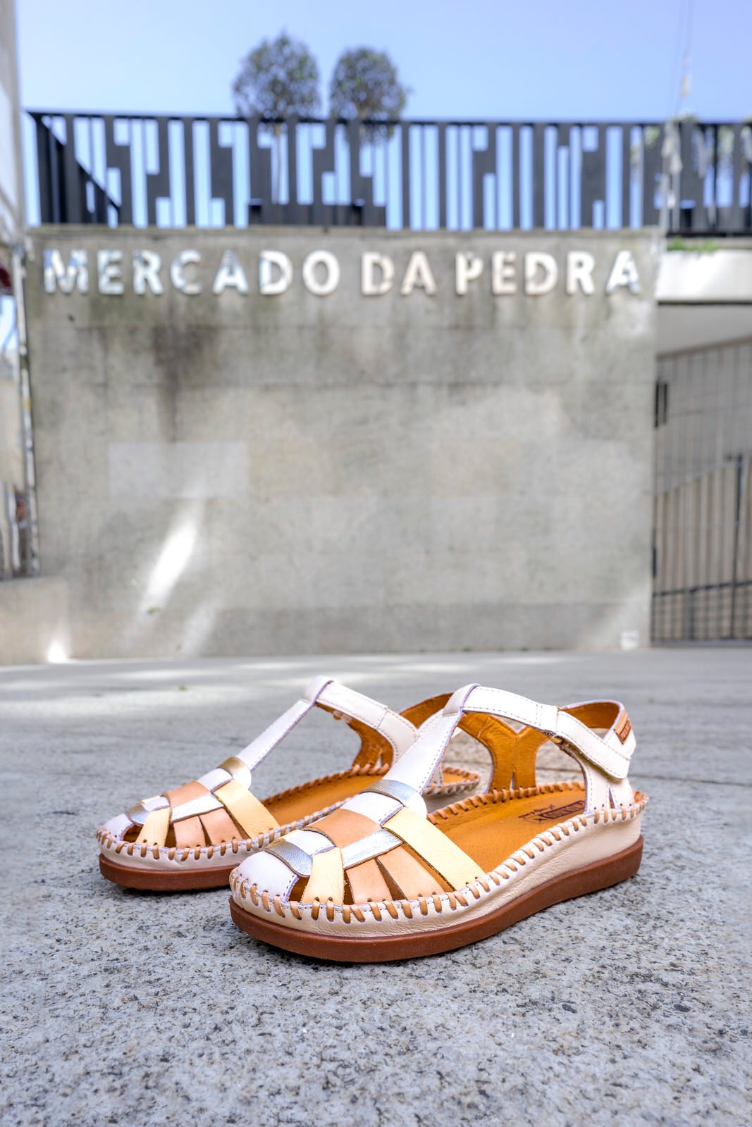 Image of a pair of women's Pikolinos sandals on the ground and, in the background, you can see the Mercado de la Piedra.