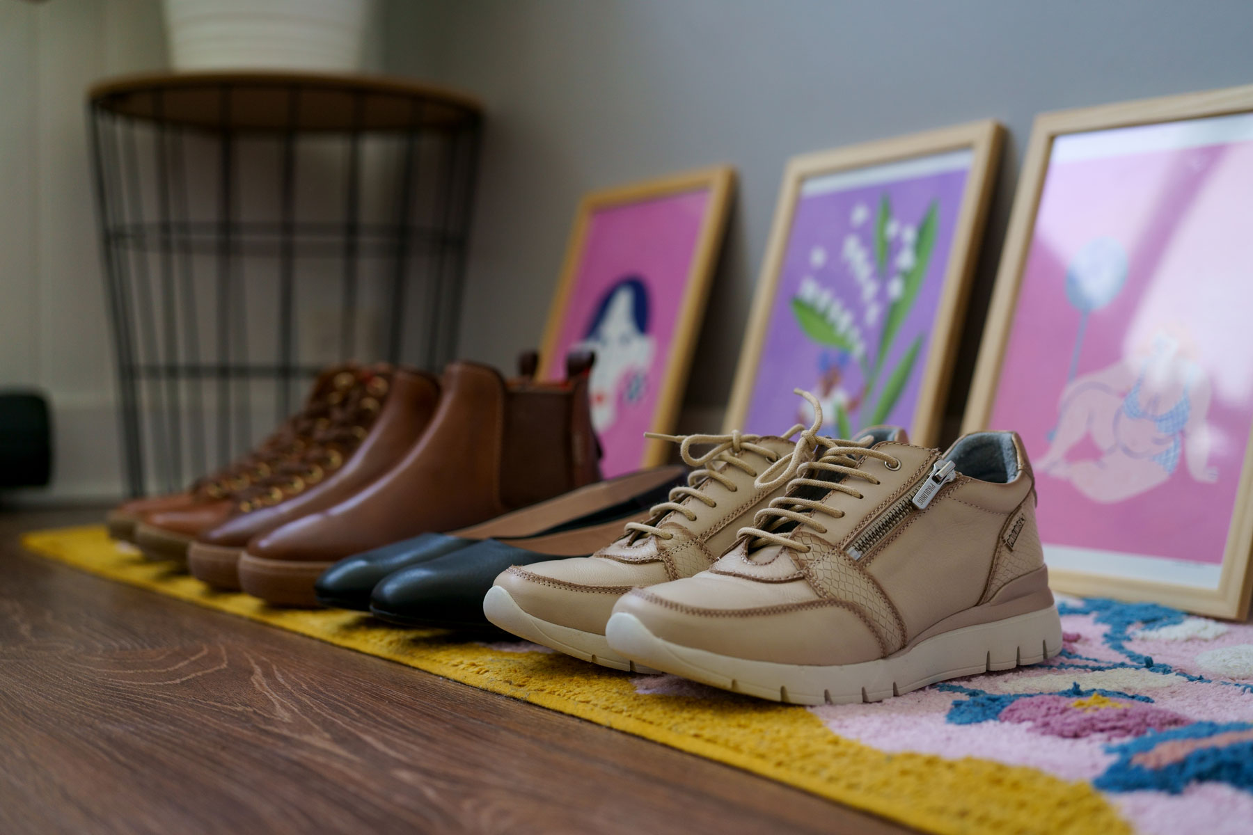 Photograph of various women's shoes of different styles from Pikolinos, on a piece of furniture
                            with paintings in the background painted by Marie.