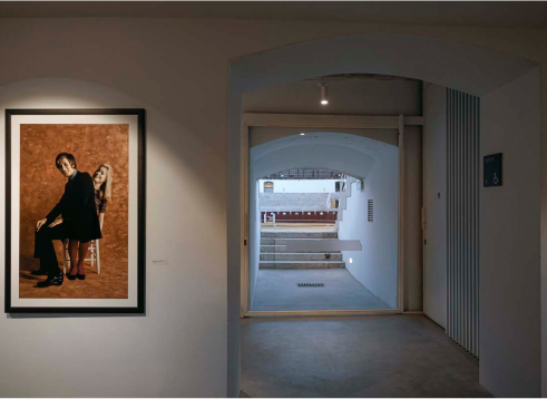 Photograph of a wall with a painting and the interior of the bullring.