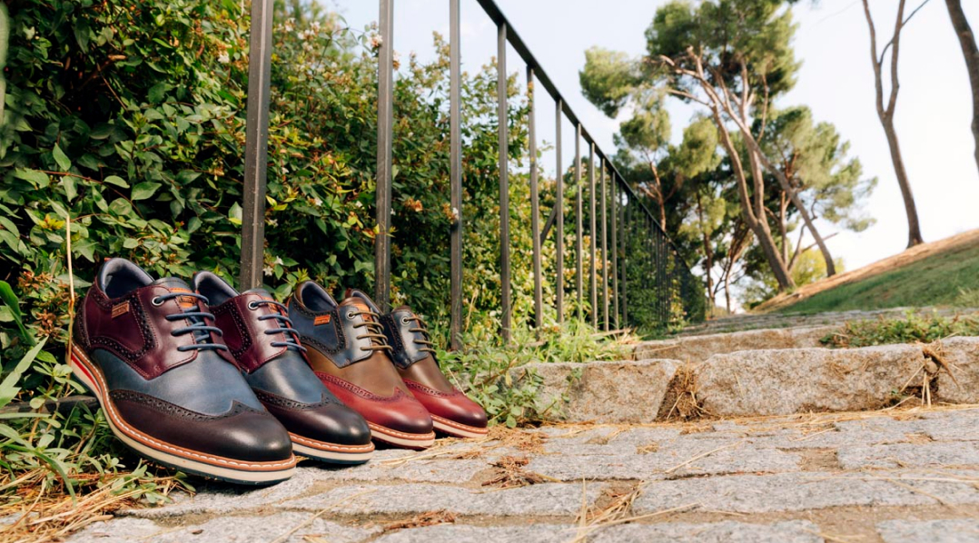 1. Image of 2 pairs of Pikolinos mens shoes resting on some stone stairs in the countryside.