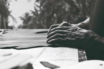 Black and white image of hands working on the skin. They are hands of a mature
                    man.