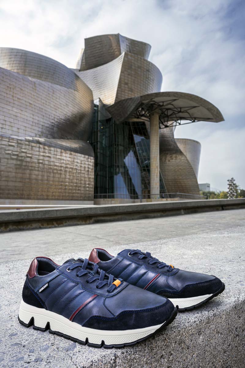 Photograph of a pair of navy blue Pikolinos men's sneakers with the Guggenheim museum in the background