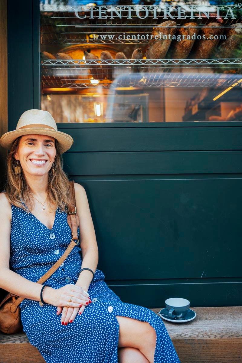 Photograph of a woman sitting with a coffee in the window of the Ciento Treinta Grados bakery.