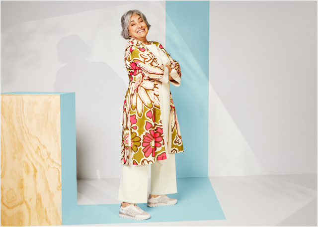 Mujer de pie, con un traje blanco y levita de flores posando con el modelo Cantabria de
                                Pikolinos