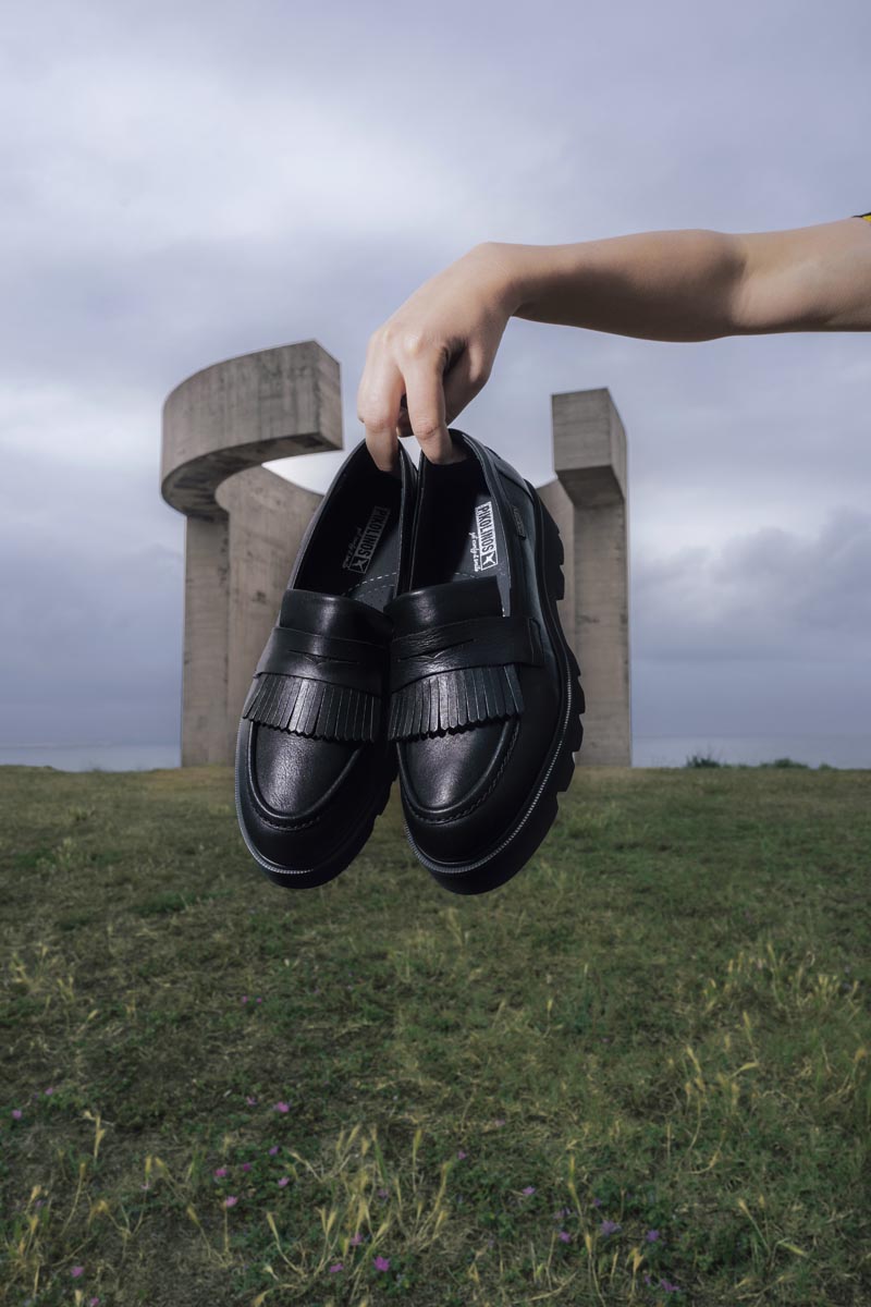 Bild eines Paars Pikolinos-Schuhe mit dem Hügel Santa Catalina im Hintergrund.
                        