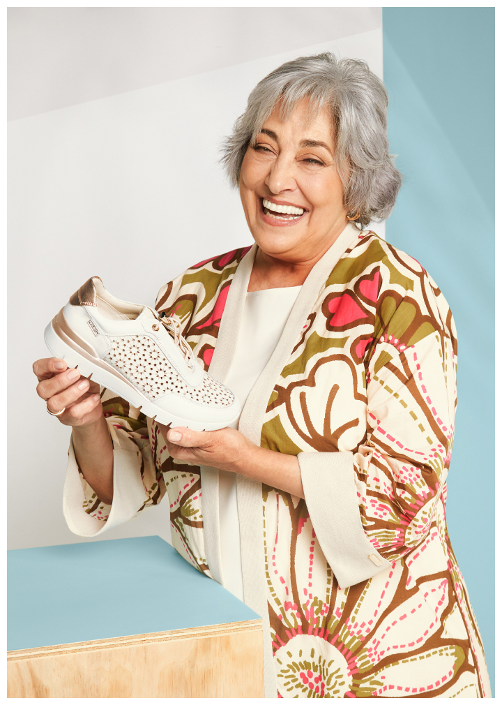 Imagen de una mujer sonriendo con un zapato deportivo en las manos.