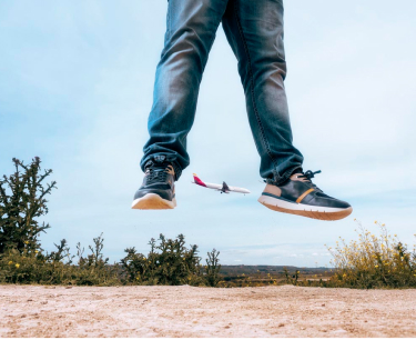 Foto von Albertos Beinen in der Luft, die mit einigen Pikolinos-Turnschuhen und einem Flugzeug im Hintergrund springen.
