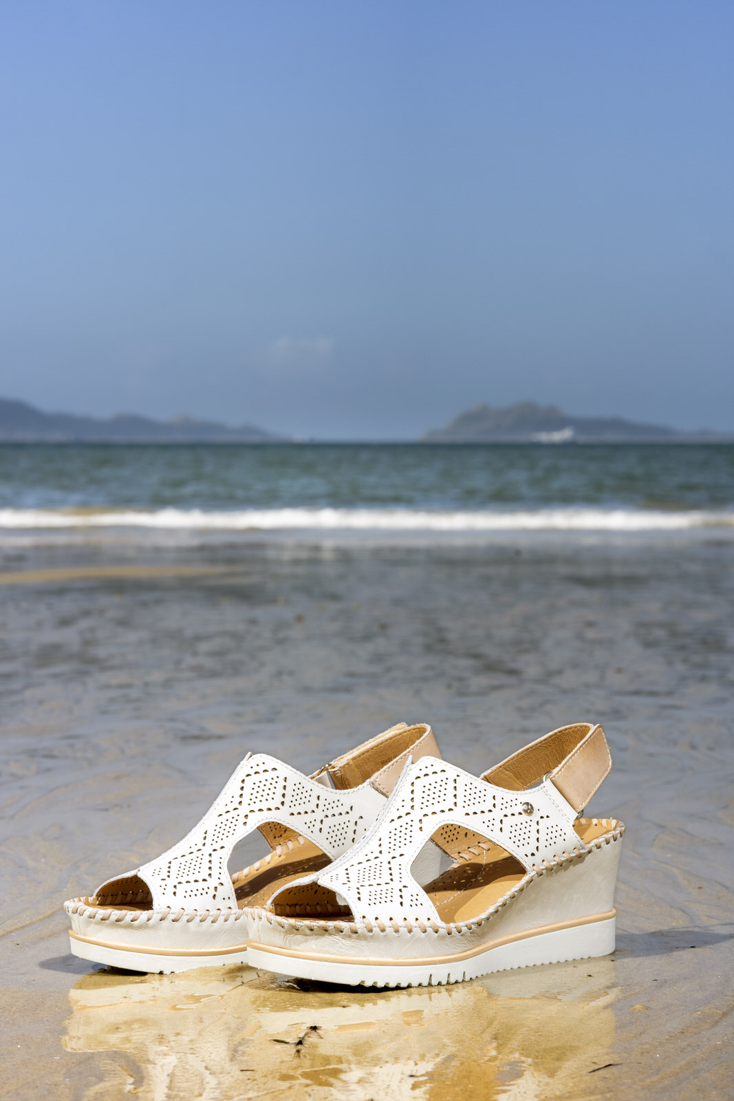 Image of a pair of women's Pikolinos sandals on a rock on the beach