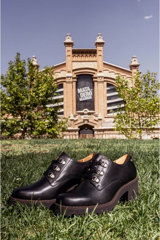 Bild eines Paars Pikolinos-Schuhe mit dem Gebäude des Madrider Schlachthofs im Hintergrund.