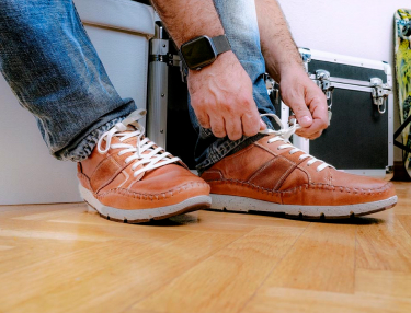 Photographie des pieds d'Alberto nouant les lacets de baskets Pikolinos.