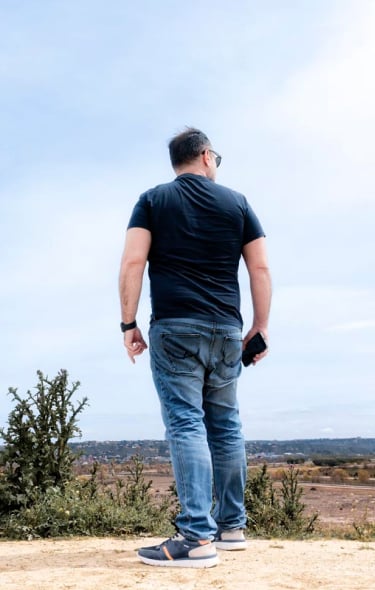 Photograph of Alberto Alonso from behind with Pikolinos sports cars and the sky and a landscape in the background.