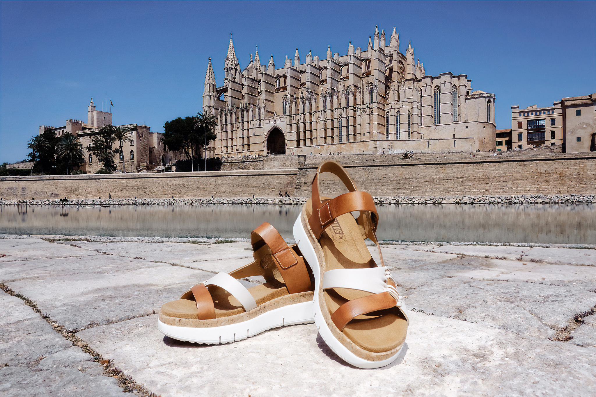Photograph of a pair of Pikolinos women's sandals in the park by the sea with the cathedral in the background