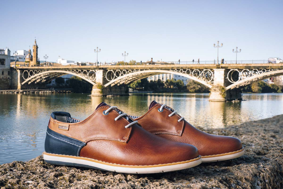 Photograph of men's shoes from Pikolinos and a bridge and the river in the background