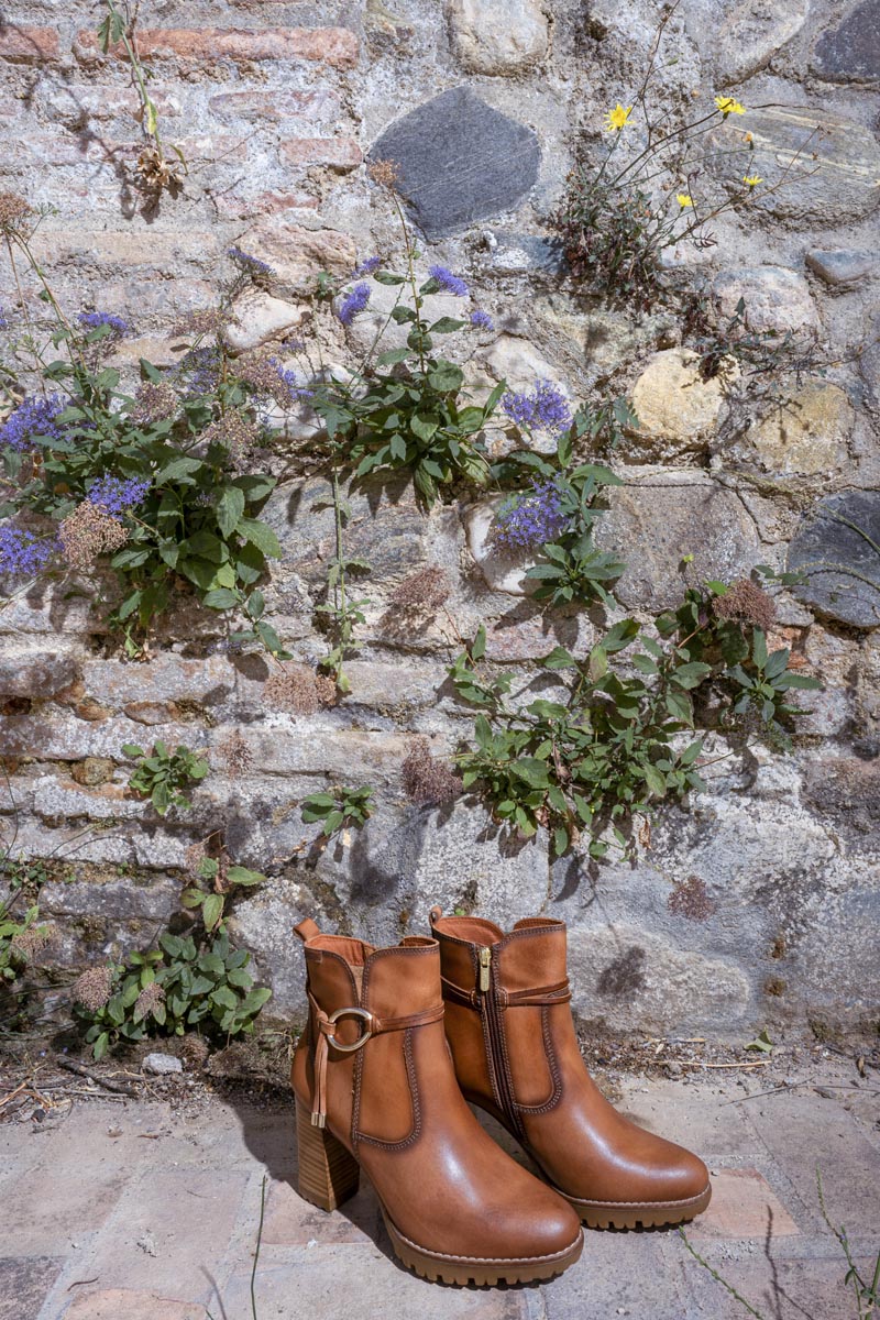 Image of Pikolinos women's heeled ankle boots on a wall with flowers