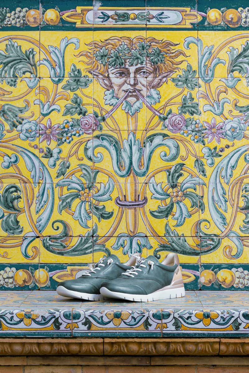 Photograph of women's green Pikolinos sneakers and a decorated tiled wall in the background