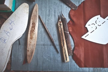 Shoemaking tools on a table, with scraps of skins.