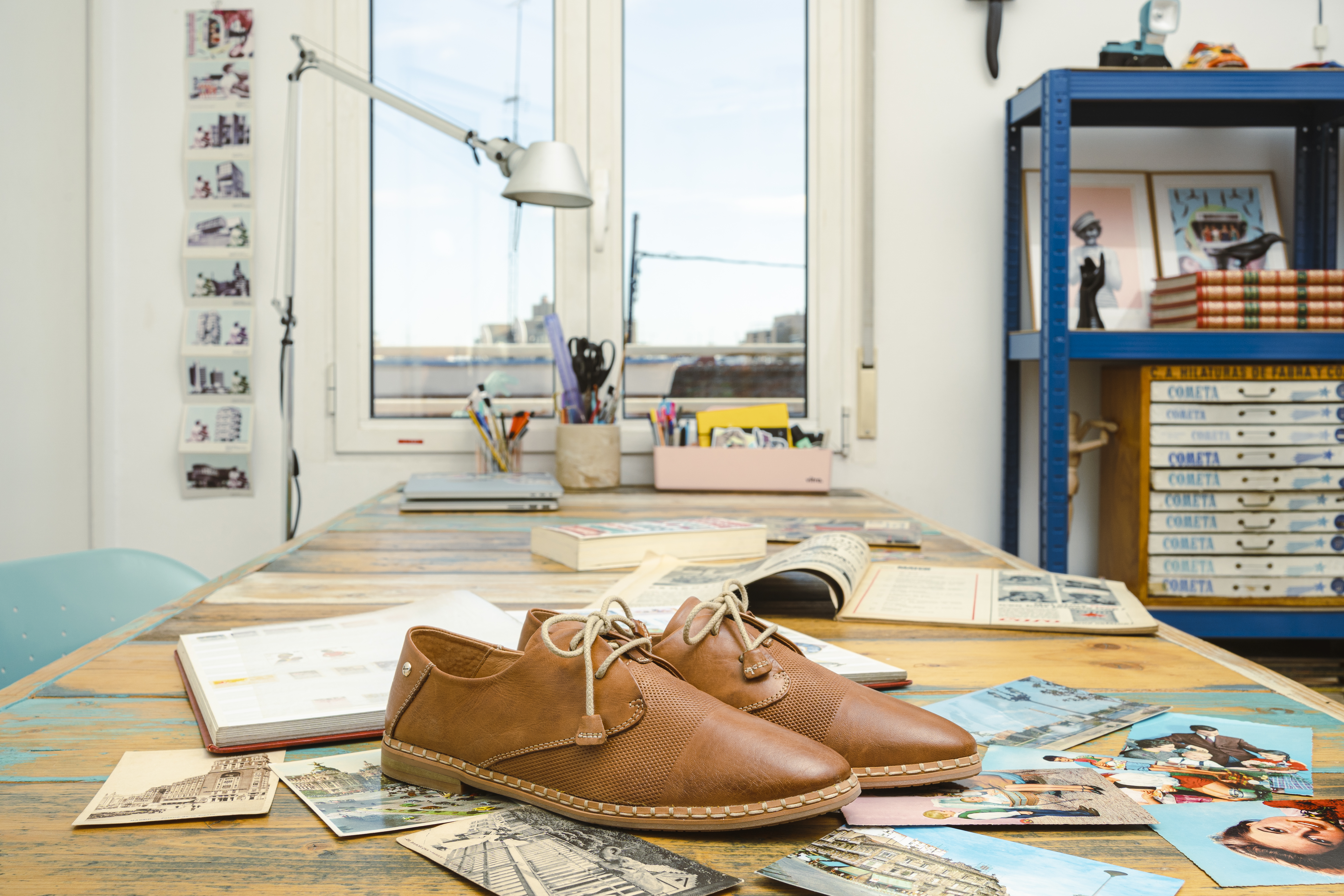 A pair of women's brown Pikolinos shoes on a worktable in front of a window.