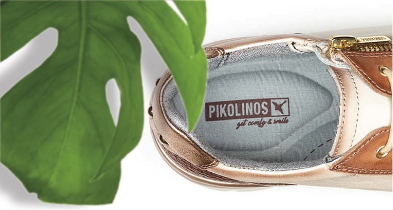 Cropped image of the insole of a women's sneakers in a shapphire color with the Pikolinos logo with a green leaf on a white background.
