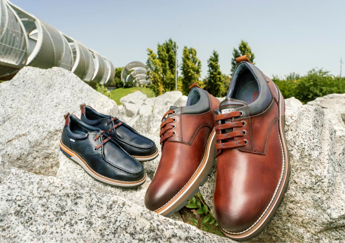 Image of 2 pairs of Pikolinos shoes leaning on a rock by the river in Madrid.