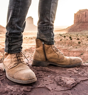 Image of man's ankle boot on a dirt floor